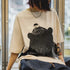 Person wearing a beige t-shirt with a black bear graphic design.